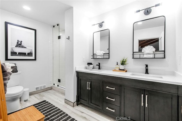 bathroom with vanity, a shower with shower door, toilet, and wood-type flooring