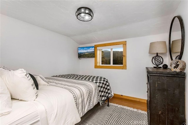 bedroom with wood-type flooring and vaulted ceiling