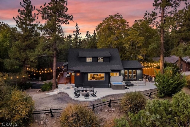 back house at dusk with a patio and a hot tub