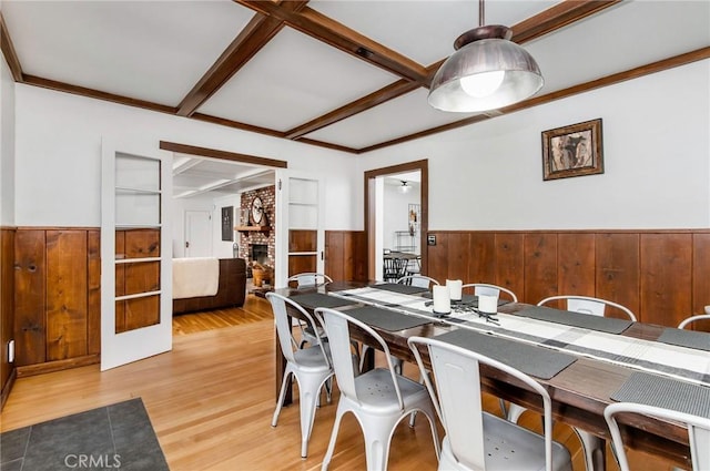 dining room with hardwood / wood-style floors, beam ceiling, and a brick fireplace