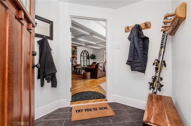 mudroom with coffered ceiling, beam ceiling, and dark tile patterned floors