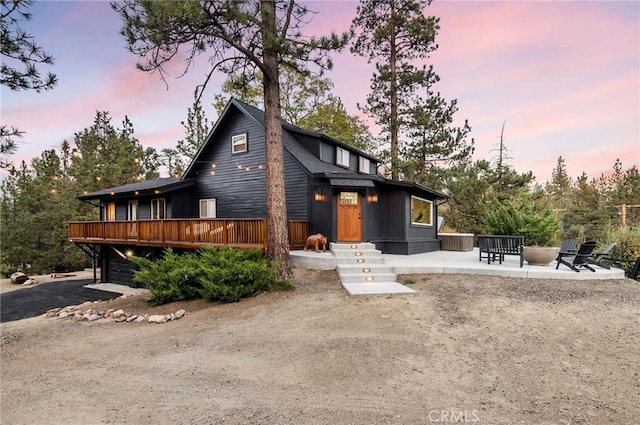 view of front facade featuring a wooden deck and a patio