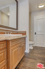 bathroom with vanity, toilet, and hardwood / wood-style floors