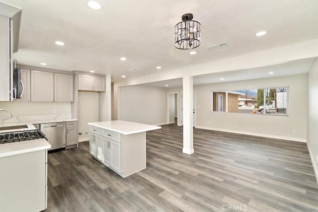 kitchen with decorative light fixtures, appliances with stainless steel finishes, dark hardwood / wood-style floors, and a kitchen island