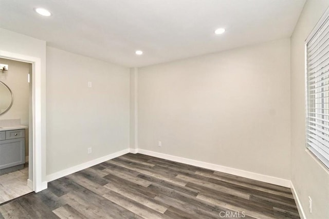 unfurnished bedroom featuring ensuite bathroom and dark wood-type flooring