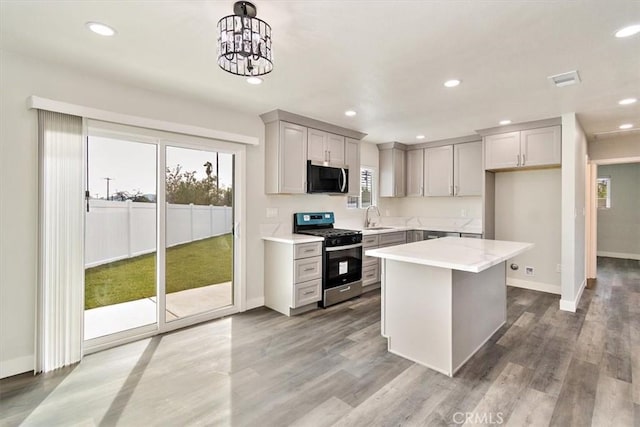 kitchen with a center island, gray cabinetry, sink, decorative light fixtures, and stainless steel appliances