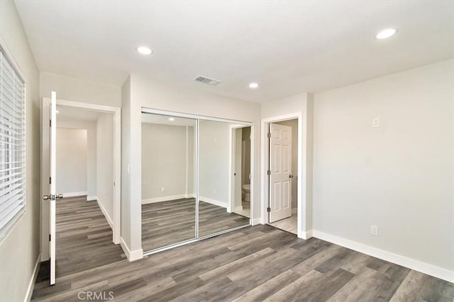 unfurnished bedroom featuring a closet and dark hardwood / wood-style flooring