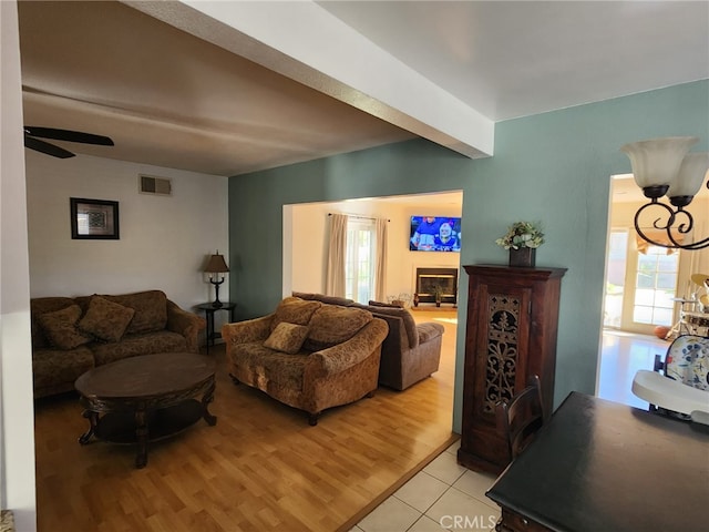 living room featuring ceiling fan, a healthy amount of sunlight, beam ceiling, and light wood-type flooring