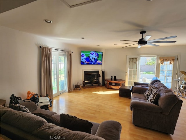 living room with a wealth of natural light, light hardwood / wood-style floors, and ceiling fan