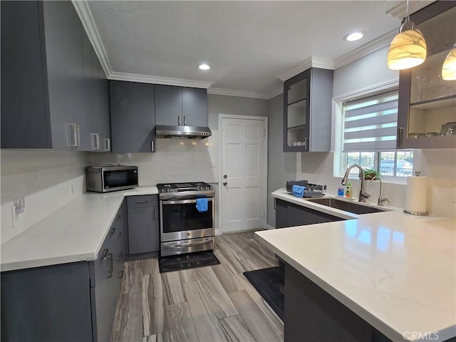 kitchen featuring pendant lighting, kitchen peninsula, appliances with stainless steel finishes, and sink