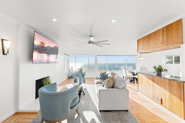 living room featuring ceiling fan, light parquet flooring, a fireplace, and ornamental molding