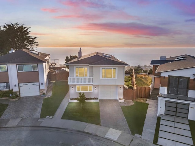 view of front of home featuring a garage, a balcony, a water view, and a lawn