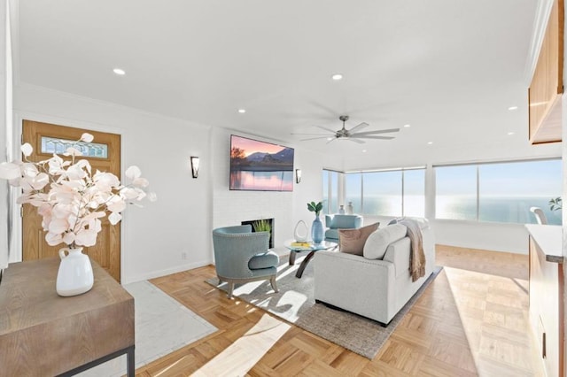 living room with light parquet flooring, crown molding, ceiling fan, and a fireplace