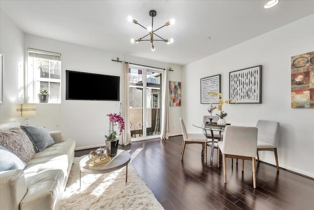 living room with dark hardwood / wood-style flooring, a healthy amount of sunlight, and an inviting chandelier