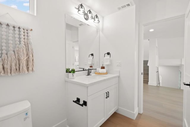 bathroom with vanity, toilet, and hardwood / wood-style floors