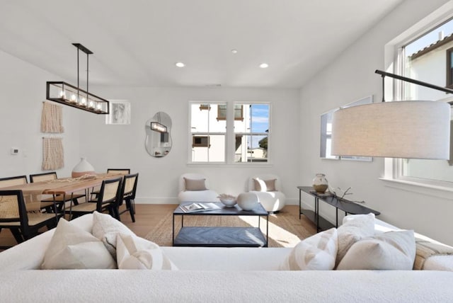 living room featuring a healthy amount of sunlight, a chandelier, and light wood-type flooring