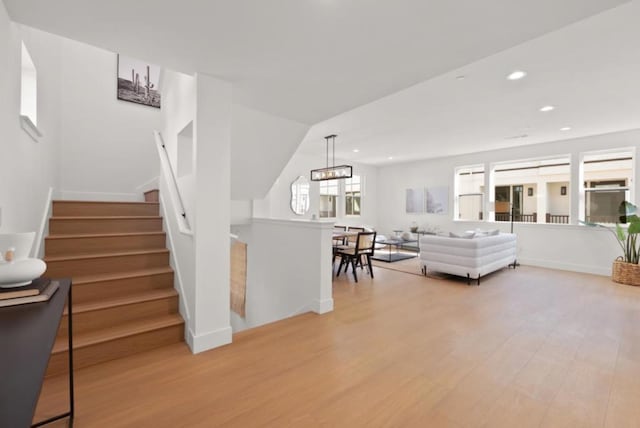 living room with an inviting chandelier, lofted ceiling, and light wood-type flooring