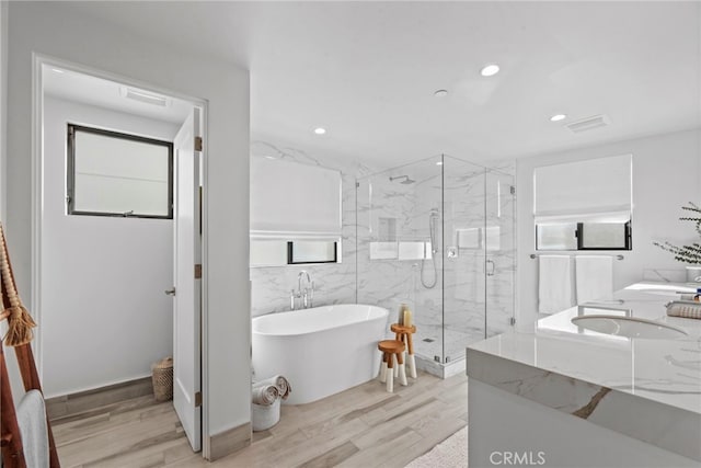 bathroom with hardwood / wood-style floors, tile walls, and plus walk in shower