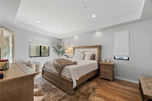 bedroom featuring light hardwood / wood-style floors and a tray ceiling