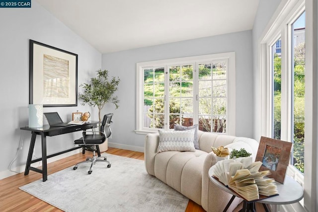 home office featuring lofted ceiling, hardwood / wood-style flooring, and a healthy amount of sunlight