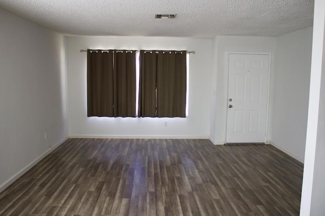 spare room with a textured ceiling and dark hardwood / wood-style flooring