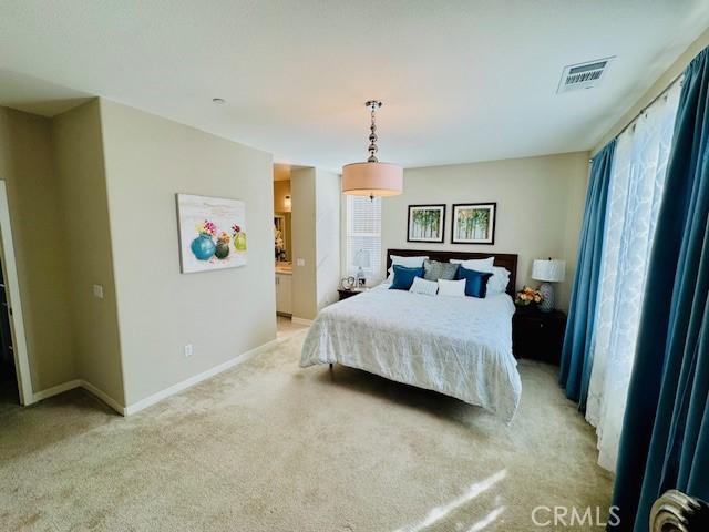 bedroom featuring ensuite bathroom and light carpet