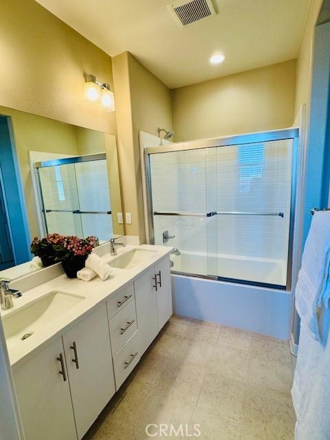 bathroom featuring bath / shower combo with glass door and vanity