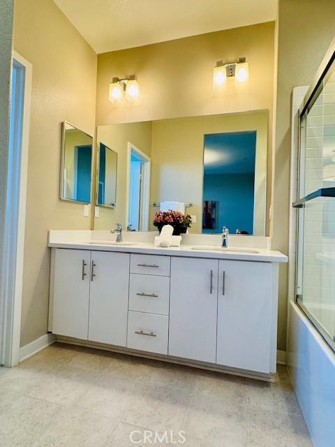 bathroom with combined bath / shower with glass door, vanity, and tile patterned flooring