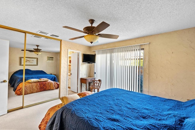 bedroom with a textured ceiling, a closet, carpet, a wall unit AC, and ceiling fan