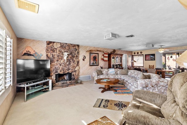 living room featuring a fireplace, carpet, ceiling fan, and wooden walls