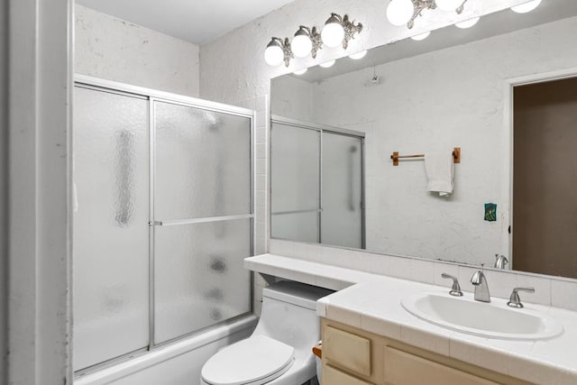 full bathroom featuring combined bath / shower with glass door, toilet, and vanity