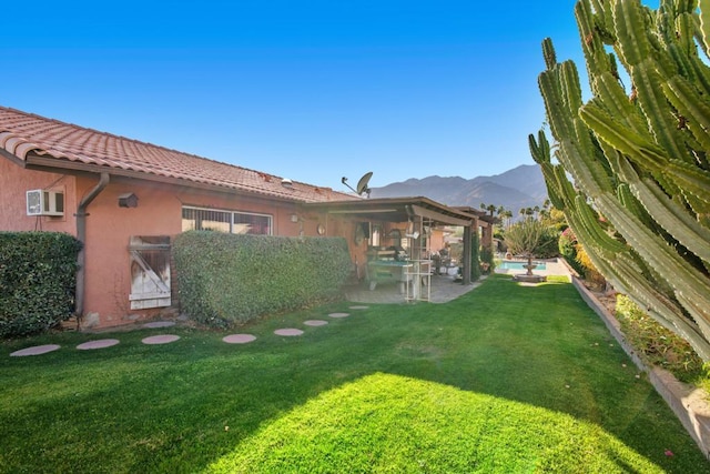 view of yard with a mountain view, a patio, and an AC wall unit