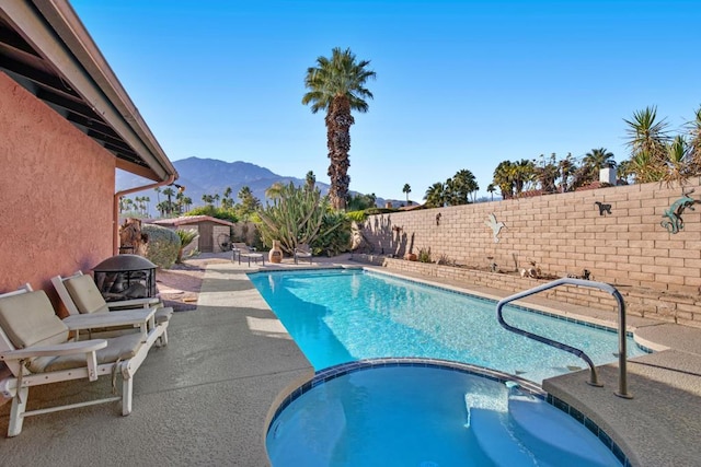 view of pool with an in ground hot tub, a mountain view, and a patio area