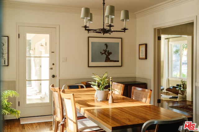 dining area featuring crown molding, wood-type flooring, and an inviting chandelier