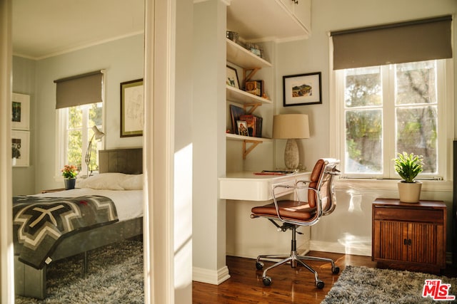 bedroom featuring dark wood-type flooring, ornamental molding, and built in desk