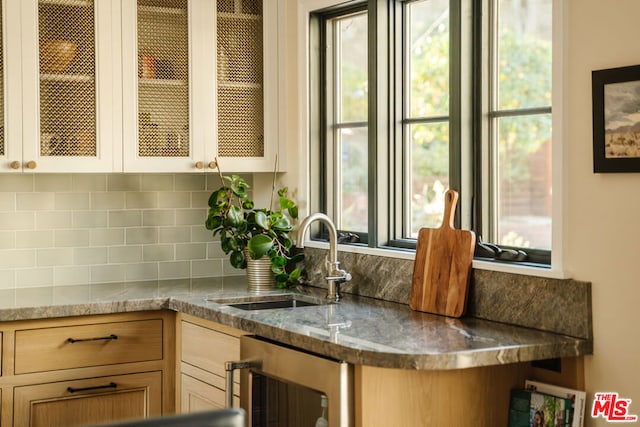 kitchen featuring a healthy amount of sunlight, sink, beverage cooler, and backsplash