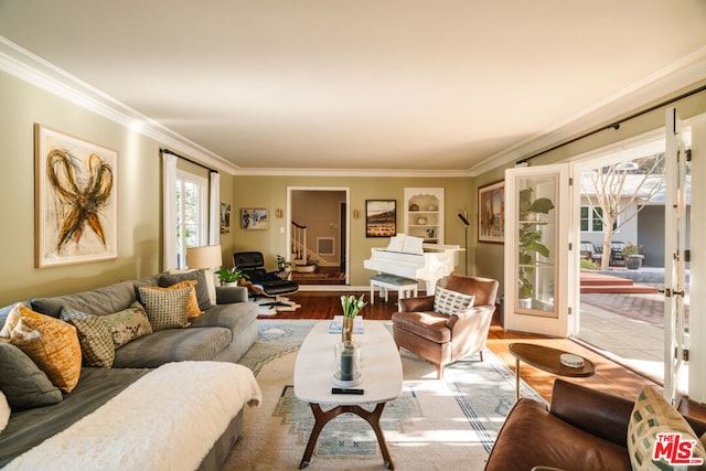 living room with hardwood / wood-style flooring, ornamental molding, built in shelves, and french doors