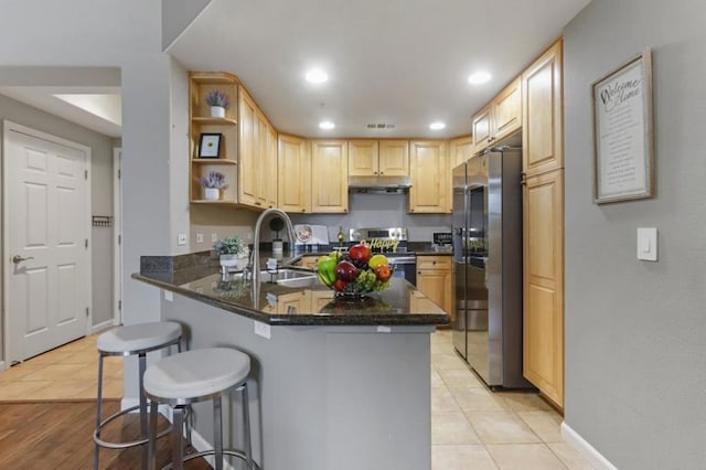 kitchen with appliances with stainless steel finishes, a kitchen breakfast bar, kitchen peninsula, and light tile patterned floors