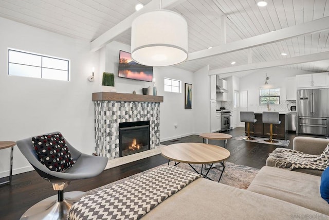 living room with a fireplace, dark hardwood / wood-style flooring, a healthy amount of sunlight, and vaulted ceiling with beams