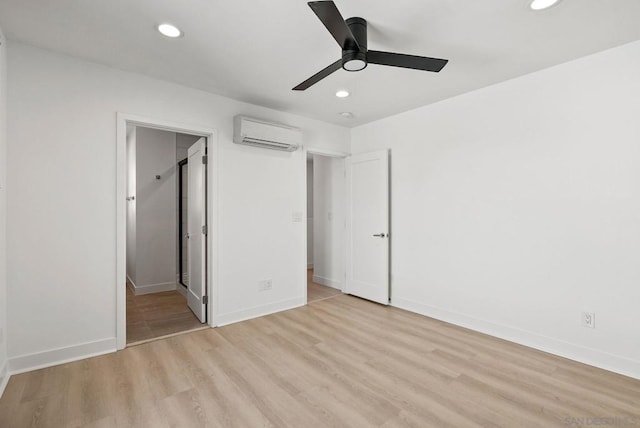 unfurnished bedroom with ceiling fan, an AC wall unit, and light hardwood / wood-style floors