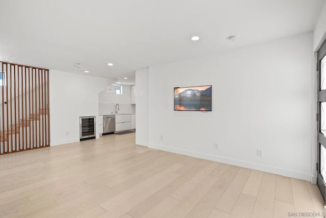 unfurnished living room with light hardwood / wood-style flooring, indoor wet bar, and beverage cooler