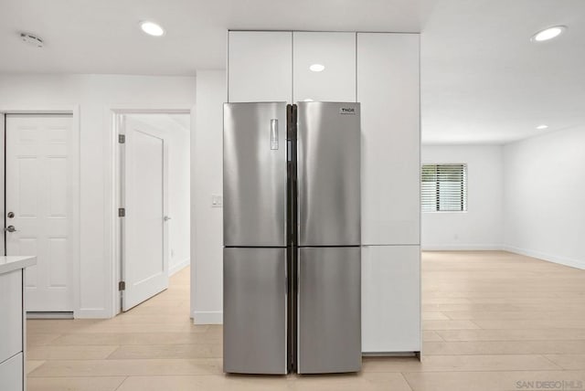 kitchen with light hardwood / wood-style floors, white cabinetry, and stainless steel fridge