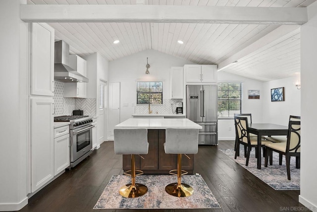 kitchen featuring a kitchen island, white cabinets, high end appliances, and wall chimney range hood