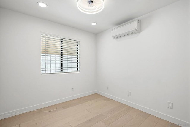 spare room featuring an AC wall unit and light hardwood / wood-style flooring