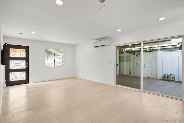 empty room with light wood-type flooring and a wall mounted air conditioner