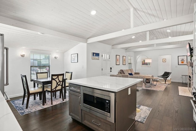 kitchen with a center island, dark hardwood / wood-style floors, lofted ceiling with beams, stainless steel microwave, and dark brown cabinets