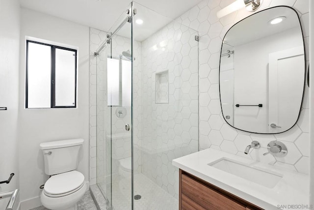 bathroom featuring vanity, toilet, tile walls, and a shower with door