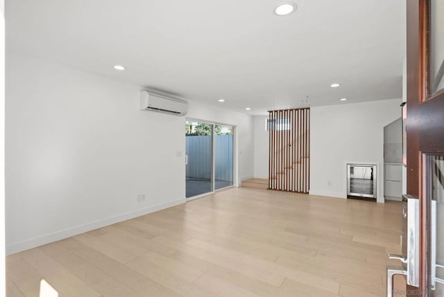 empty room featuring light wood-type flooring and a wall mounted air conditioner