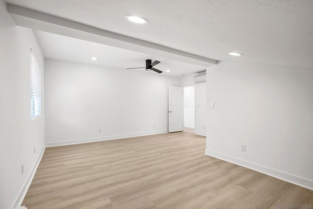 spare room featuring a wall mounted AC, light hardwood / wood-style flooring, and ceiling fan