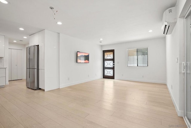 spare room featuring light hardwood / wood-style flooring and a wall mounted AC